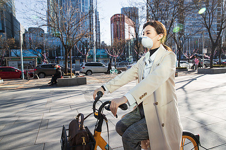 白领戴口罩的年轻女人骑共享单车图片