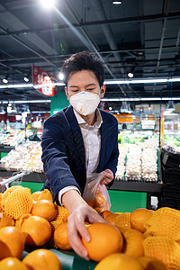 戴口罩的青年男人在超市挑选水果图片