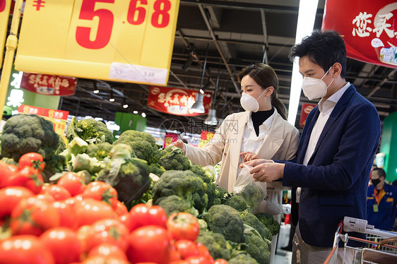 城市生活青年夫妇戴口罩在超市挑选蔬菜图片