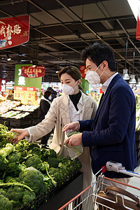 户内摆放健康保健青年夫妇戴口罩在超市挑选蔬菜高清图片
