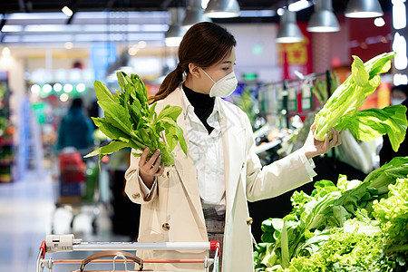 消费戴口罩的青年女人在超市购买青菜图片