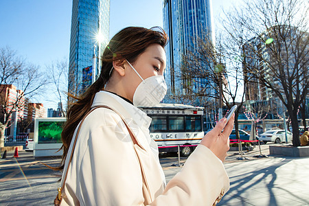 预防新型冠状戴口罩的青年女人看手机图片