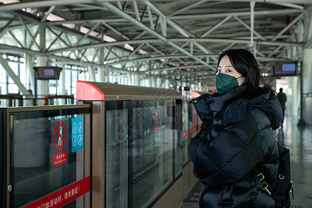 戴口罩的年轻女人站在地铁站台上图片