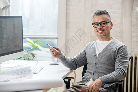 在室内研究图纸的中老年设计师男士图片