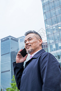 商务男士站着楼群中间打电话图片