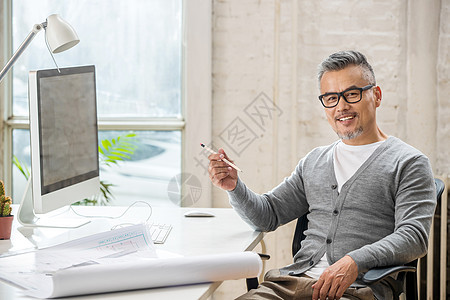 在室内研究图纸的中老年设计师男士图片