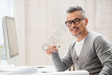 在室内研究图纸的中老年设计师男士图片