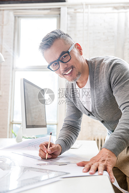 在室内研究图纸的中老年设计师男士图片