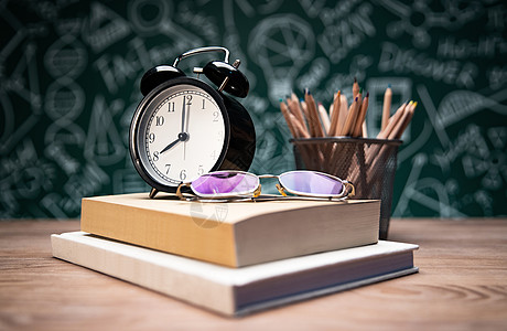 黑板上的字母黑板画前的桌子上的学习用品和眼镜背景