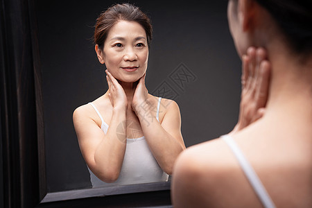 中年女人对着镜子做颈部护理图片