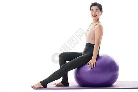 快乐的中年女坐在瑜伽球上图片