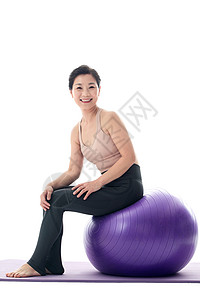 中年女坐在瑜伽球上休息图片