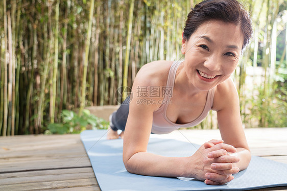 木地板户外中老年女士趴着练瑜伽图片