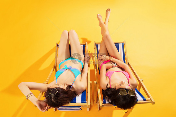 清爽自由比基尼闺蜜坐在沙滩上日光浴图片