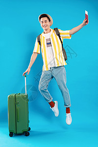 扶着行李箱跳跃的年轻男人图片