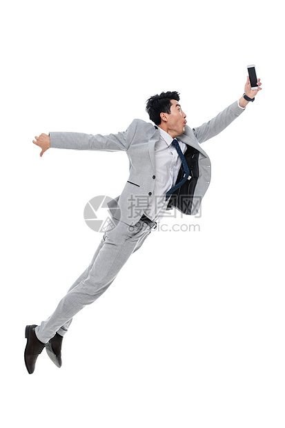 有趣的面部表情户内拿着手机奔跑跳跃的商务男士图片