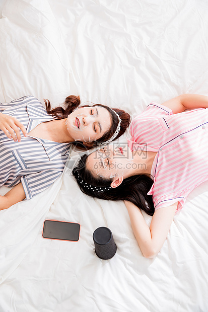 活力年轻闺蜜躺在床上敷面膜图片