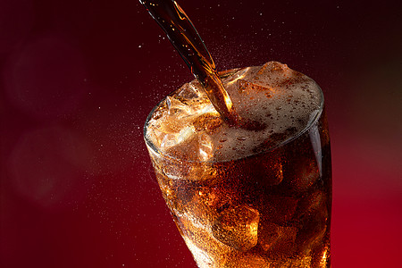 可乐倒入装满冰块的杯中图片