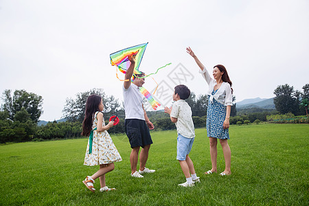 夏天生态旅游水平构图快乐的一家四口在草地上放风筝图片