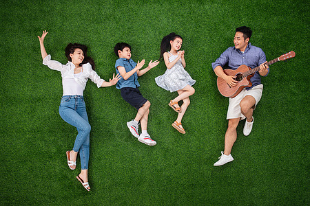 青年人侧卧青年女人幸福的一家四口在草地上唱歌图片