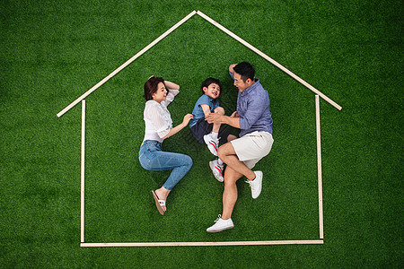 理想和现实正上方视角25岁到29岁陪伴快乐的一家三口躺在草地上的房子轮廓里玩耍背景