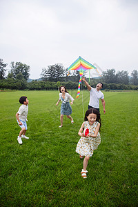青年夫妇垂直构图8到9岁快乐的一家四口在草地上放风筝图片
