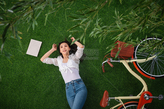 休闲装竹子享乐躺在草地上享受大自然的青年女人图片