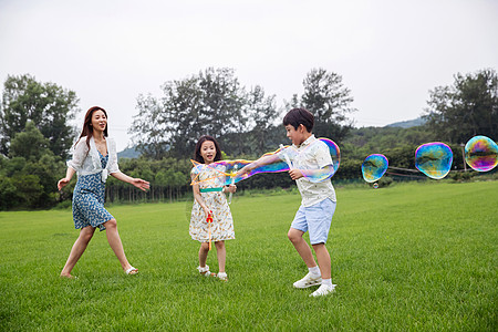 敢爱敢玩色微笑无忧无虑兴奋妈妈带着两个孩子在草地上快乐玩耍背景