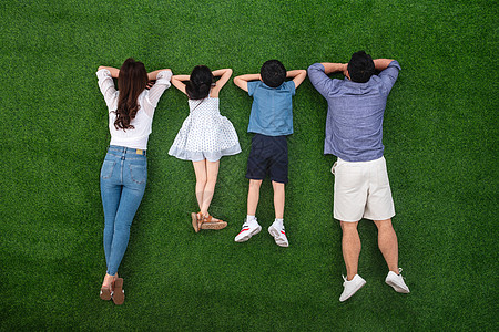 亚洲四个人短裤幸福的一家四口趴在草地上图片