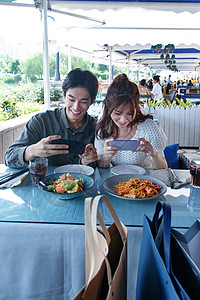 餐客一体青年情侣在餐厅里用手机拍照背景
