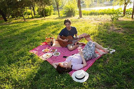 无忧无虑休闲不看镜头在公园里弹吉他的幸福情侣图片