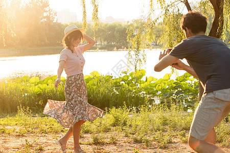荷叶和女孩男朋友夏天白昼幸福情侣在公园里拍照背景