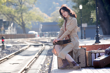 全身像青年人旅行青年女人坐在火车站站台上图片