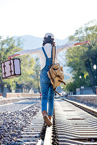 休闲装不看镜头欢乐青年女人徒步走在铁轨上图片