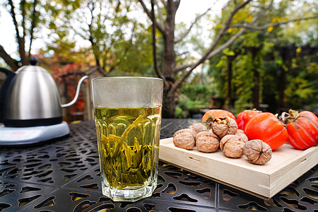 不锈钢茶壶庭院桌子上的茶和柿子核桃背景