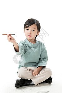 无忧无虑留白愉悦可爱的小男孩坐在地上用毛笔写字背景图片