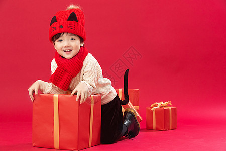 传统庆典包装盒祝福可爱的小男孩趴在新年礼物上玩耍图片