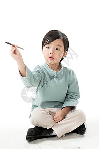 全身像欢乐古典式可爱的小男孩坐在地上用毛笔写字图片