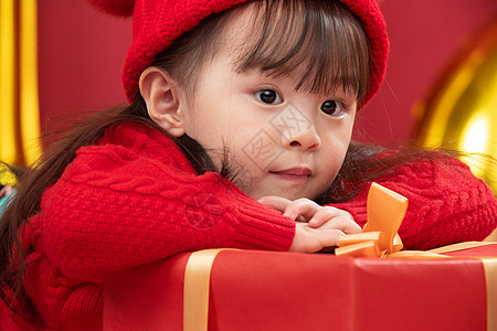 影棚拍摄传统庆典人可爱的小女孩趴在新年礼物上图片