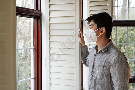 透过窗外向外看戴口罩的男孩高清图片
