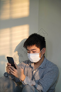 防护戴口罩的男孩看手机图片