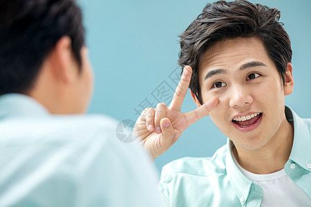 造型休闲无忧无虑自信的年轻男人对着镜子做手势图片