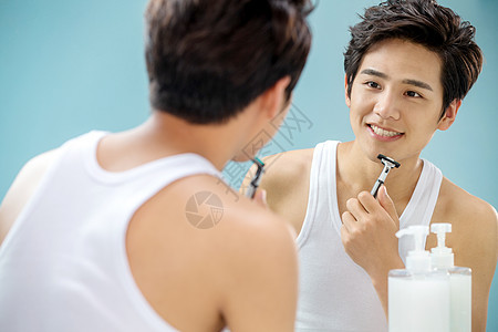 青年男人对着镜子刮胡子图片