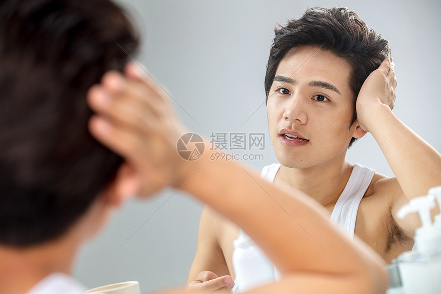 完美自我完善照着镜子整理发型的年轻男人图片