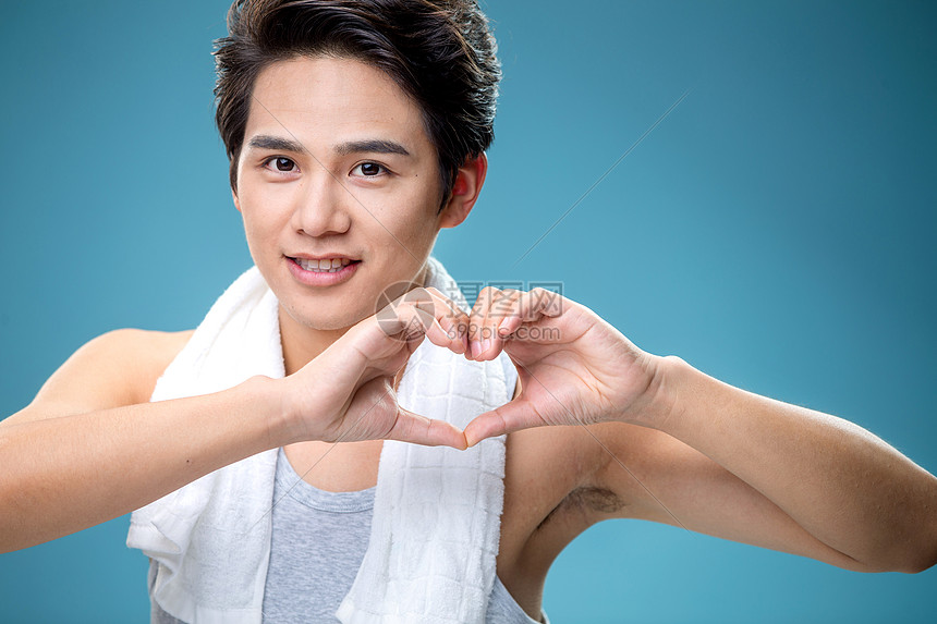 注视镜头青年人肩膀上搭着毛巾用手比心的年轻男人