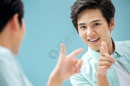 选择对焦头和肩膀自信的年轻男人对着镜子做手势图片