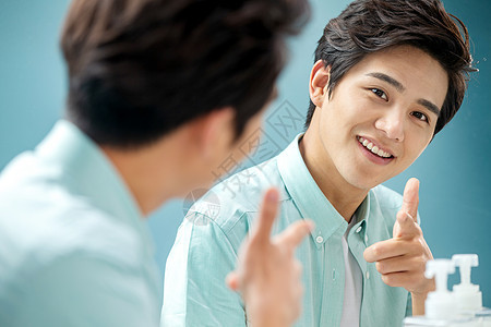 欣赏亚洲青年文化自信的年轻男人对着镜子做手势图片