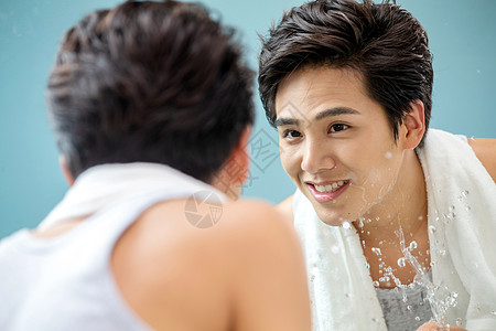 清新笑亚洲人年轻男人对着镜子洗脸图片