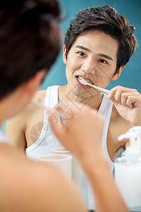 健康生活方式蓝色背景彩色图片年轻男人对着镜子在刷牙图片
