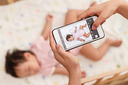 孩子睡觉妈妈给婴儿床上的宝宝照相背景